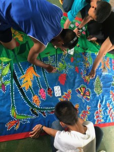 Young artists applying the dotting pattern around the flora and fauna.