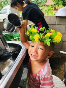 Little Waput helps out with the dishes in his crown of flowers